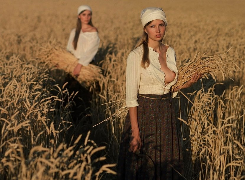 two socialist women gathering grain and showing a little tit, but not happy about it